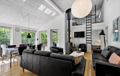 a living room with black couches and a dining room at Cozy Home In Ringkøbing With Sauna in Ringkøbing