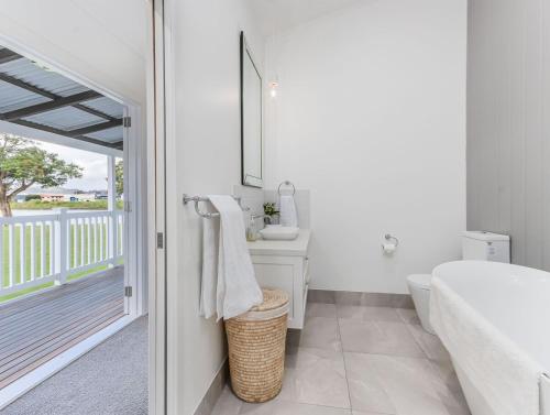 a bathroom with a sink and a toilet and a tub at Hamptons White House in Murwillumbah