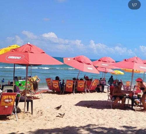 a group of people sitting under umbrellas on a beach at Pousada vitoria praia de serrambi-pe in Ipojuca