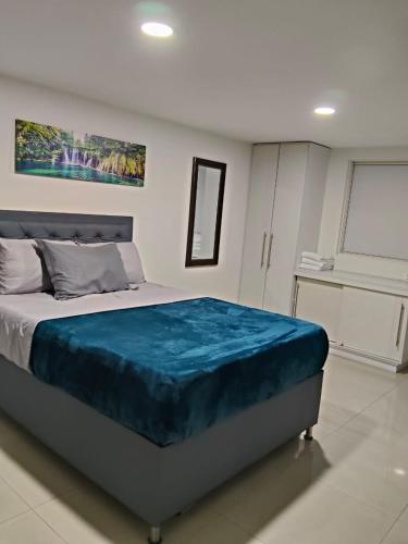 a bedroom with a bed with a blue blanket on it at Glam House Hotel in Medellín