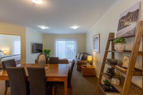 a dining room and living room with a table and chairs at Lifestyle Apartments at Ferntree in Fern Tree Gully