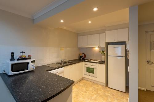 a kitchen with white cabinets and a white refrigerator at Lifestyle Apartments at Ferntree in Fern Tree Gully
