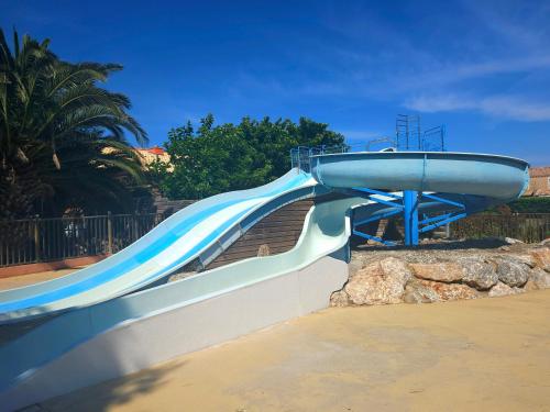 un toboggan bleu et blanc dans une aire de jeux dans l'établissement Charmante maisonnette - Piscine, sauna, jacuzzi, au Barcarès