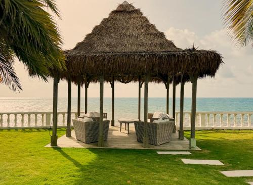 a gazebo with chairs and a table and the ocean at La Marea in Cedar Grove