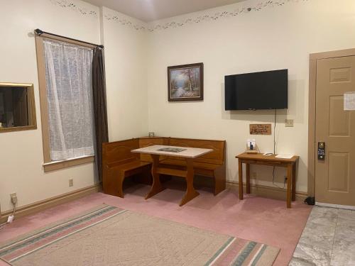 a living room with a table and a tv at Oak Valley Inn and Suites in Geneseo