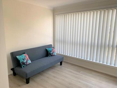 a living room with a blue couch and a large window at Shellharbour Beach Daze in Shellharbour