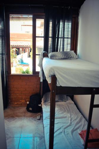 a bedroom with two bunk beds and a window at Cabo Frio Fun Hostel in Cabo Frio