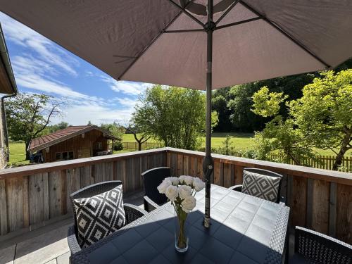 a table with a vase of flowers and an umbrella at Burg 2 - Ferienwohnungen in Taching am See