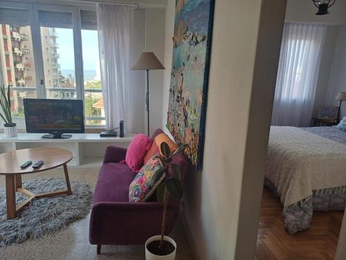 a living room with a purple couch and a bed at VENTANAS AL MAR in Mar del Plata