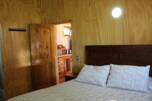 a bedroom with a bed and a door and a microwave at Cabaña Rinconada de Malalcahuello in Malalcahuello
