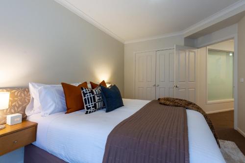 a bedroom with a large white bed with pillows at Lifestyle Apartments at Ferntree in Fern Tree Gully