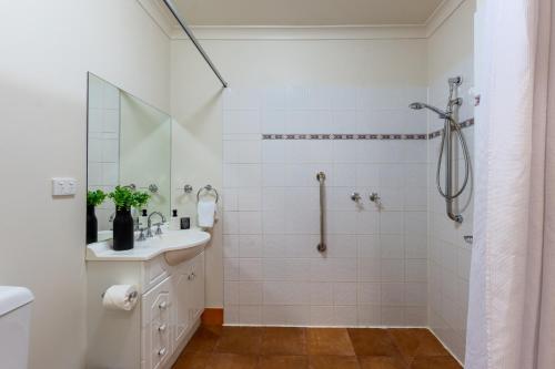 a white bathroom with a shower and a sink at Lifestyle Apartments at Ferntree in Fern Tree Gully