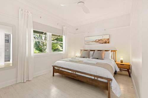 a white bedroom with a bed and two windows at Brae View House - By Latitude South Coast in Berry