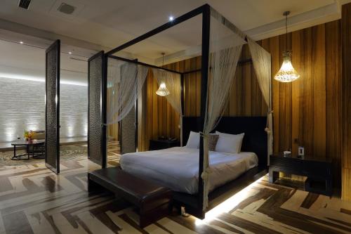 a bedroom with a canopy bed and a table at Mulan Motel in Taichung
