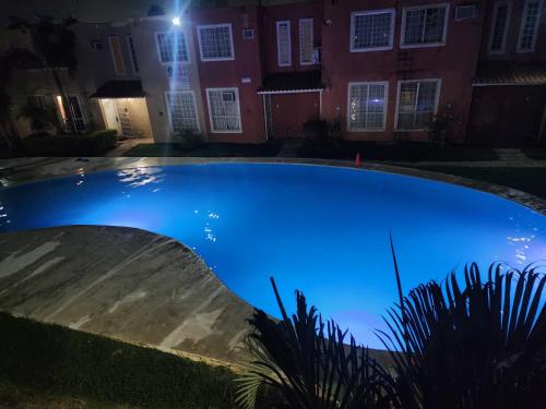a large blue swimming pool in front of a house at night at Colors Acapulco in Acapulco