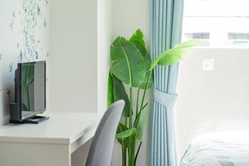 a desk with a computer and a plant next to a window at スカイテラス那覇 in Naha