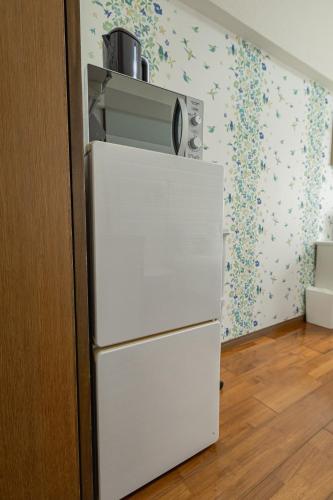 a white refrigerator with a microwave on top of it at スカイテラス那覇 in Naha