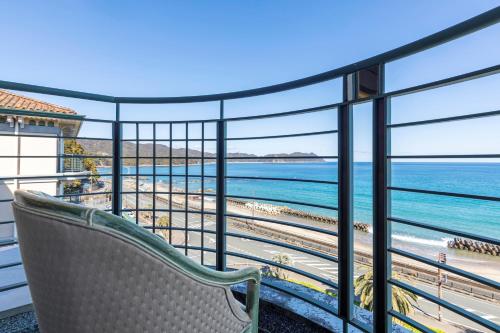 a chair on a balcony looking out at the beach at Hotel Riviera Shishikui in Kaiyo