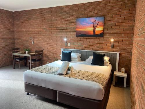 a bedroom with a large bed and a brick wall at Ashleigh Court Motor Inn in Mulwala