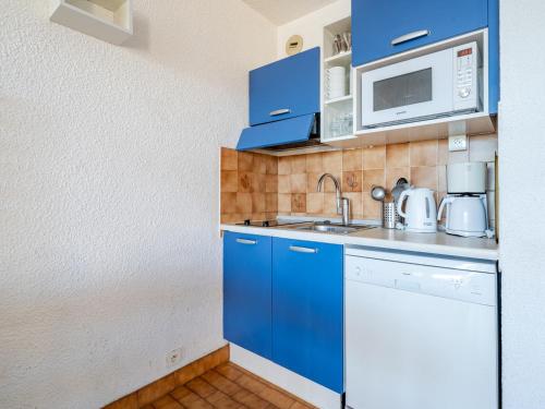 Elle comprend une petite cuisine avec des placards bleus et un four micro-ondes. dans l'établissement Appartement pour 8, spacieux séjour, vue mer, Wi-Fi inclus - FR-1-827-20, à Roquebrune-Cap-Martin