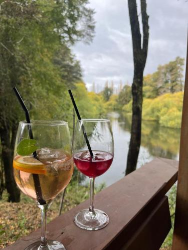 two glasses of wine sitting on a table with a view of a river at Alto Terralis in Minetué