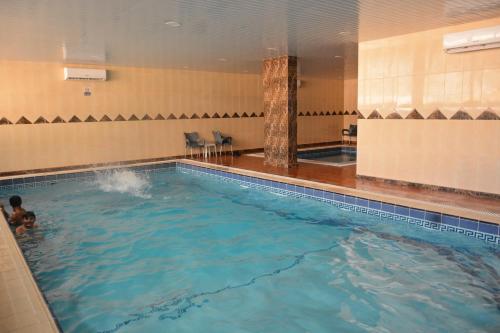 une grande piscine avec une personne dans l'eau dans l'établissement ضيافة بيت المسرة للشقق المخدومة, à Khobar