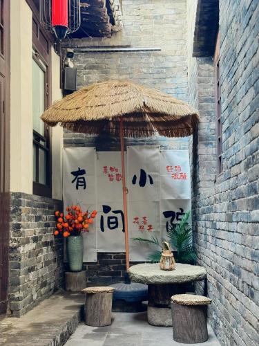a patio with a table and a straw umbrella at Elsewhere Hotel Inn Ancient City Center Branch in Pingyao