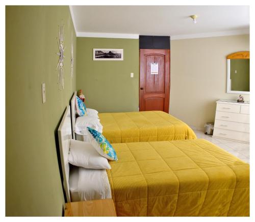 two beds in a room with green walls and yellow sheets at Hospedaje La Casa Blanca in Urbanizacion Buenos Aires