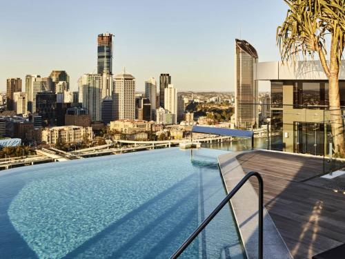 a swimming pool on the roof of a building with a city skyline at Lucid Apartments by CLLIX in Brisbane