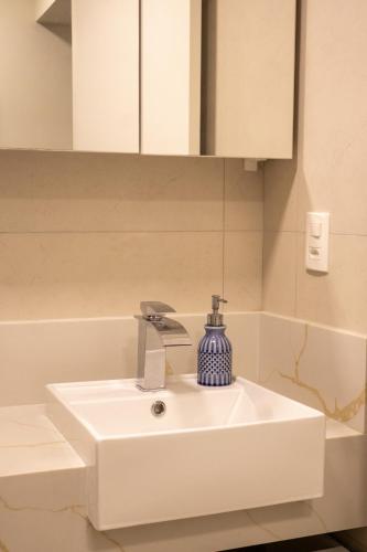 a white bathroom sink with a blue bottle on it at apto Casal Canela in Canela