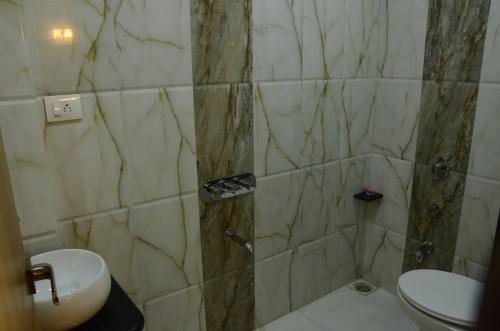 a bathroom with a shower with a toilet and a sink at Hotel Sach Regency in Anand