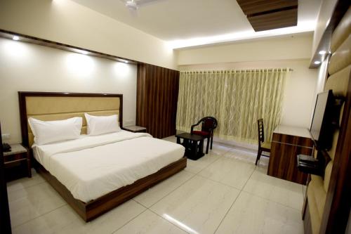 een slaapkamer met een bed, een bureau en een televisie bij Hotel Sach Regency in Anand