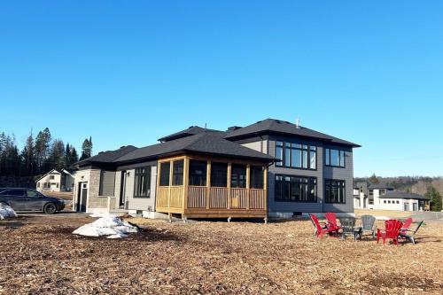 a house with a deck and chairs in front of it at Entire Home in Lake of Bays -Huntsville Muskoka Algonquin in Dwight