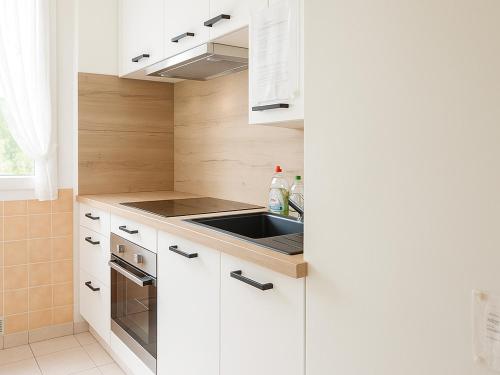 une cuisine avec des armoires blanches et un évier dans l'établissement T2 lumineux au Racou avec piscine et parking, 100m de la plage - Argelès-sur-Mer - FR-1-732-7, à Argelès-sur-Mer