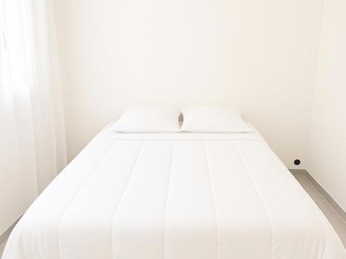 - un lit blanc dans une chambre blanche aux murs blancs dans l'établissement Appartement neuf à 50m de la plage centrale, moderne et tout confort - FR-1-732-61, à Argelès-sur-Mer