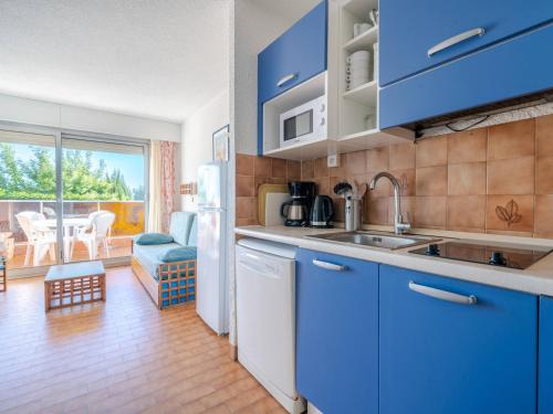 une cuisine avec des placards bleus et une grande fenêtre dans l'établissement Studio confortable, idéal pour 4 personnes avec Wi-Fi - FR-1-827-72, à Roquebrune-Cap-Martin