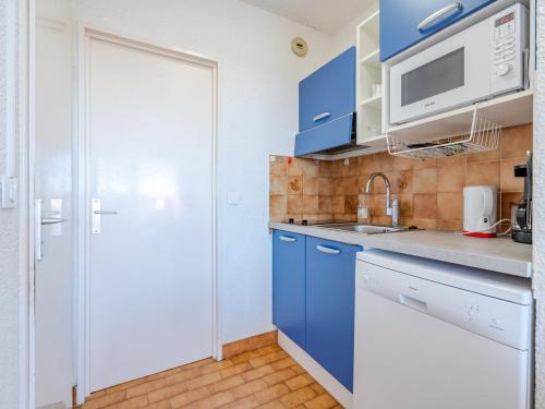 La cuisine est équipée de placards bleus et d'un réfrigérateur blanc. dans l'établissement Studio bord de mer 4 pers, Wi-Fi inclus - FR-1-827-91, à Roquebrune-Cap-Martin