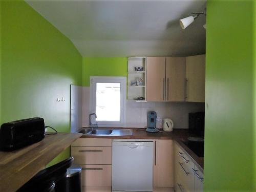 Elle comprend une petite cuisine avec des murs verts et des placards blancs. dans l'établissement Appartement Duplex, 4-6 pers, près plage, Kerjouanno, parking inclus - FR-1-639-145, à Arzon