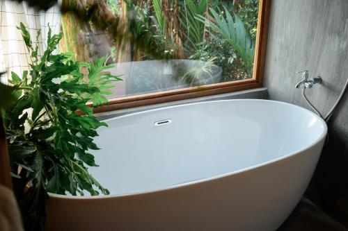 a white bath tub in a bathroom with a window at Dancasa Horse Farm & Homestay in Buôn Chiêt
