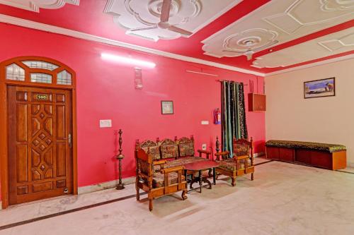 a living room with red walls and a wooden door at 81603 Hotel Shiva Grand in Chinhat