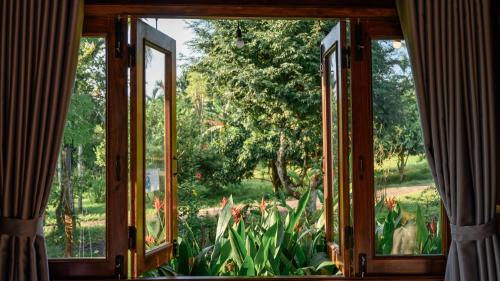 an open window with a view of a garden at Dancasa Horse Farm & Homestay in Buôn Chiêt