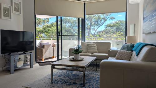 Una sala de estar con un sofá y un televisor. en Beachfront Nautilus, en Rockingham