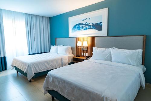 two beds in a hotel room with blue walls at Holiday Inn Acapulco La Isla by IHG in Acapulco