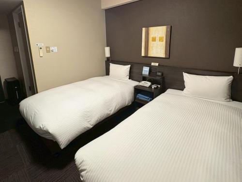 two beds sitting next to each other in a hotel room at Hotel Route-Inn Higashihiroshima Saijo Ekimae in Higashihiroshima