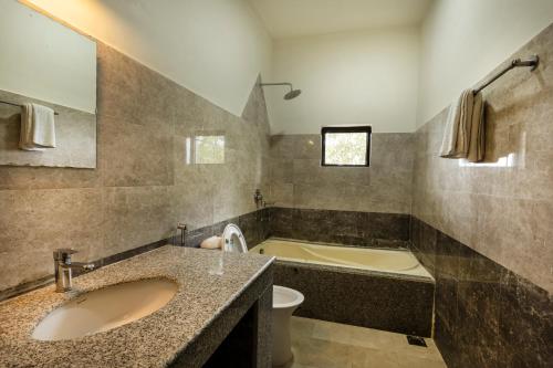 bagno con 2 lavandini, vasca e servizi igienici di Hotel Parkside & Swimming Pool-Between Greenery and Azure ,Your Perfect Retreat a Chitwan