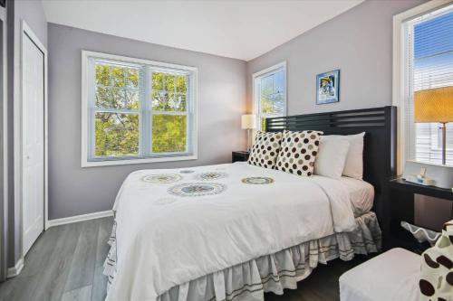 a bedroom with a large bed and two windows at Bogeys Retreat by AvantStay Golfers Retreat w Shared Pool Month Long Stays Only in Stock Island