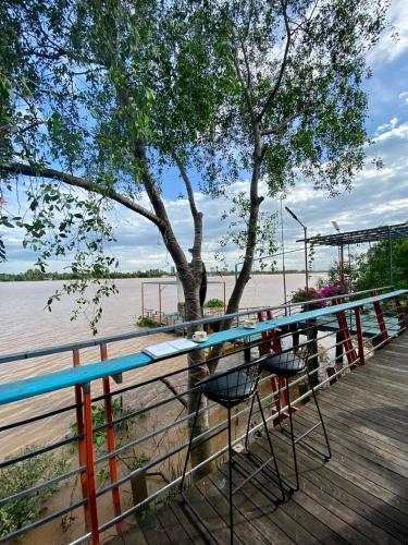 a table and chairs on a boardwalk next to a tree at Cồn Phụng Resort Mekong - Nature Escape with Free Boat Shuttle & Fishing in Ben Tre