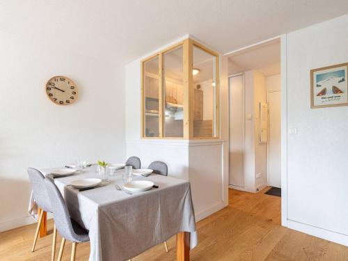 une salle à manger avec une table et une horloge au mur dans l'établissement Appartement Peyragudes 6 pers, balcon, ski, parking - FR-1-695-75, à Gouaux-de-Larboust