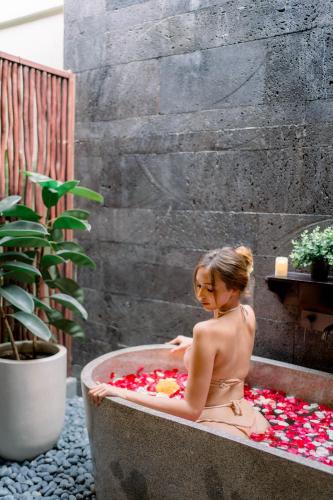 a woman sitting in a bath tub filled with flowers at Villa Bolon in Kuta