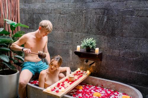 a man and woman in a bath tub with a cake at Villa Bolon in Kuta